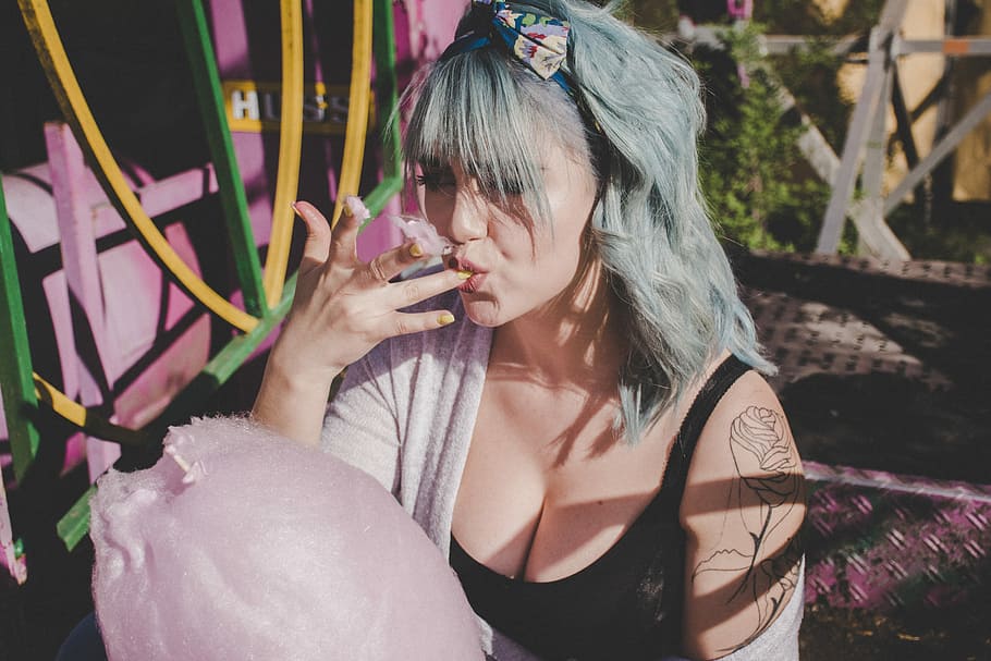 woman eating cotton candy, woman eating pink cotton candy, person