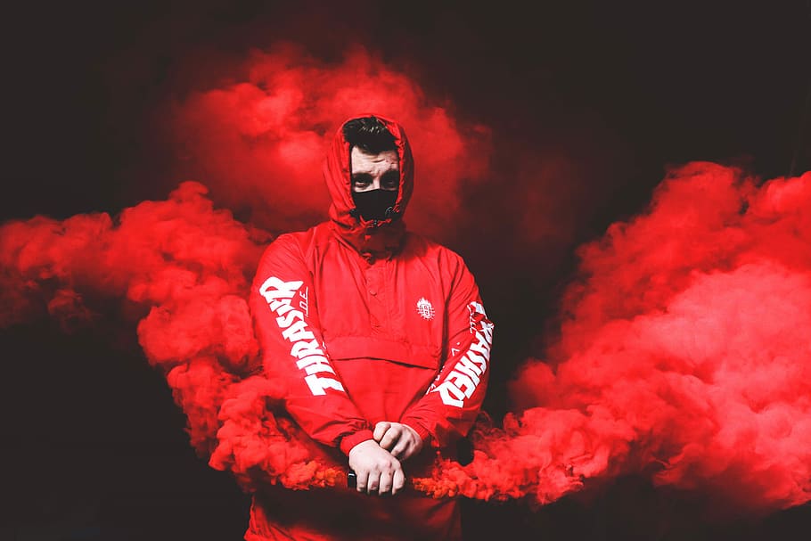 man in red Thrasher pullover hooded jacket with red smoke, man wearing red hoodie holding red smoke maker device