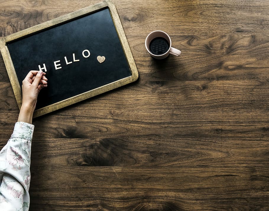 flat lay photography of person's hand on hello board beside mug HD wallpaper