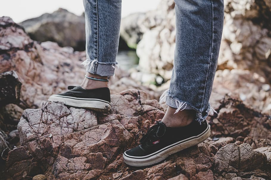 person wearing blue denim jeans and low-top sneakers standing on rock, person standing on gray rocks, HD wallpaper