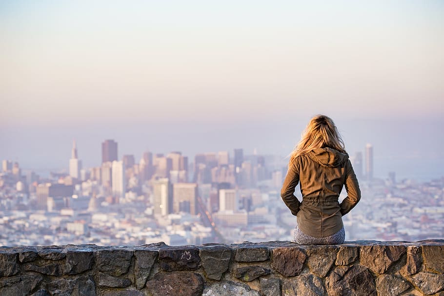 woman in brown jacket sitting on gray concrete bench during daytime, HD wallpaper