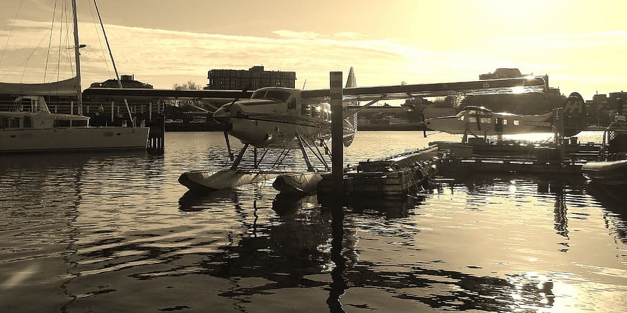 white bi-plane docked on port near white boat during daytime HD wallpaper
