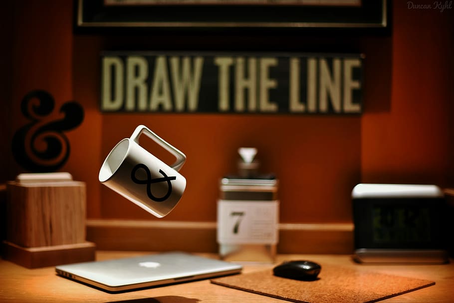 white and black Ampersand printed mug floating above brown wooden table, black and white ceramic mug with ampersand logo-printed floating near silver MacBook and black wireless computer mouse HD wallpaper