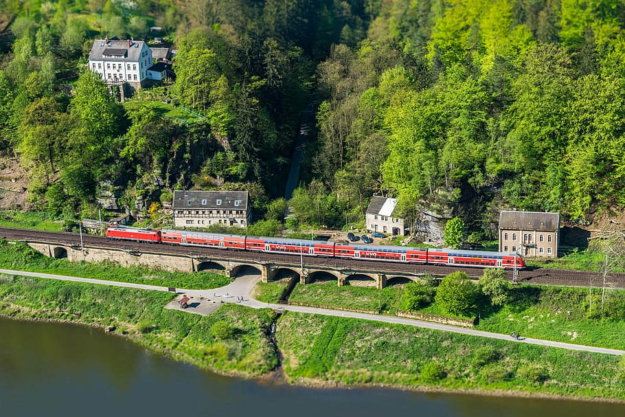 red train traveling on railway near trees, elbe, viaduct, miniature