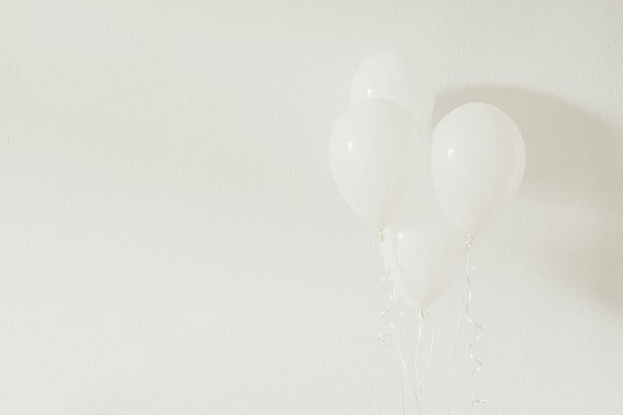 four white balloons on white wall, three floating white balloons behind white wall
