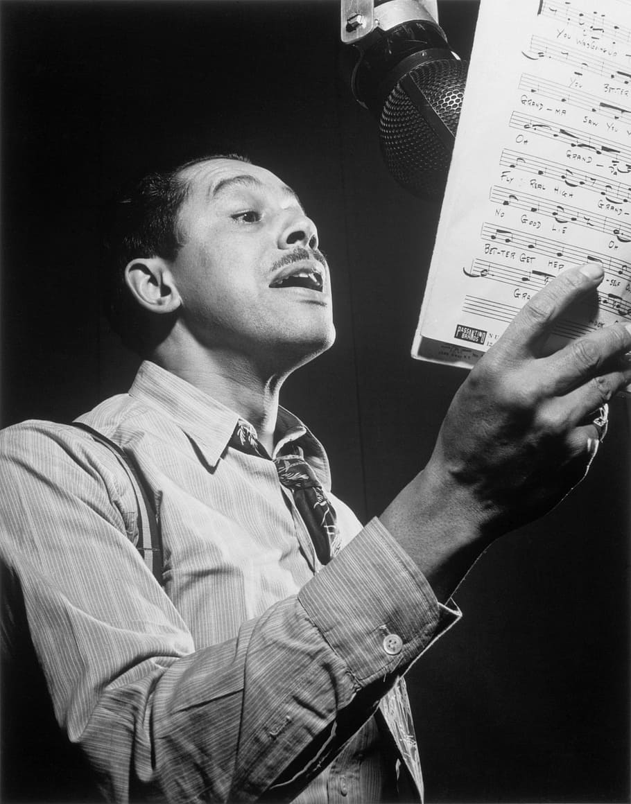 graysale photography of man singing while holding musical script HD wallpaper