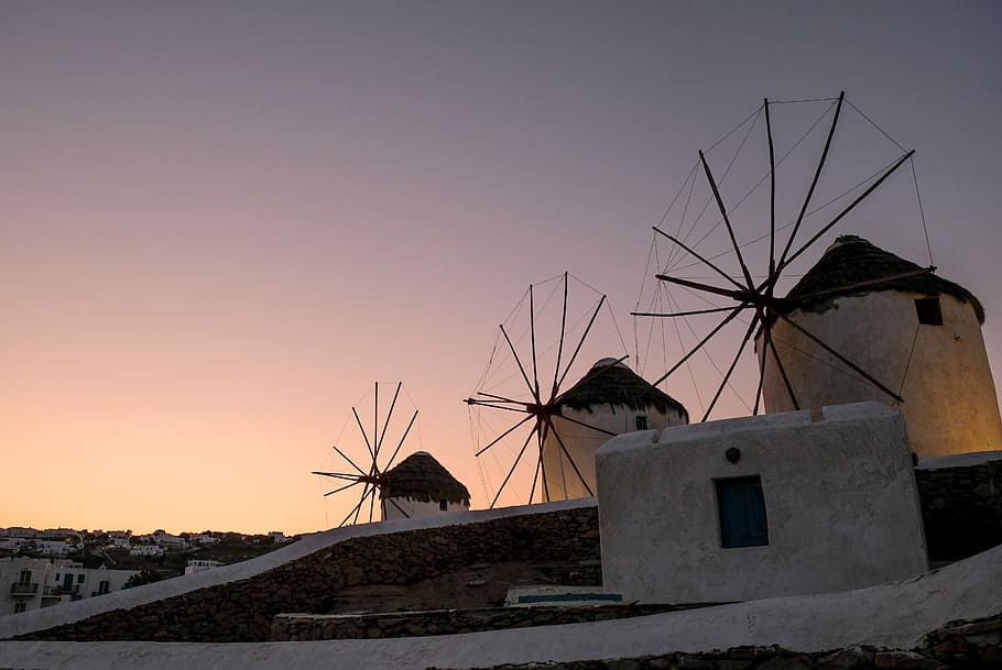 three gray concrete building at cloudy sky during daytime, three brown windmills under gray sky during sunset HD wallpaper