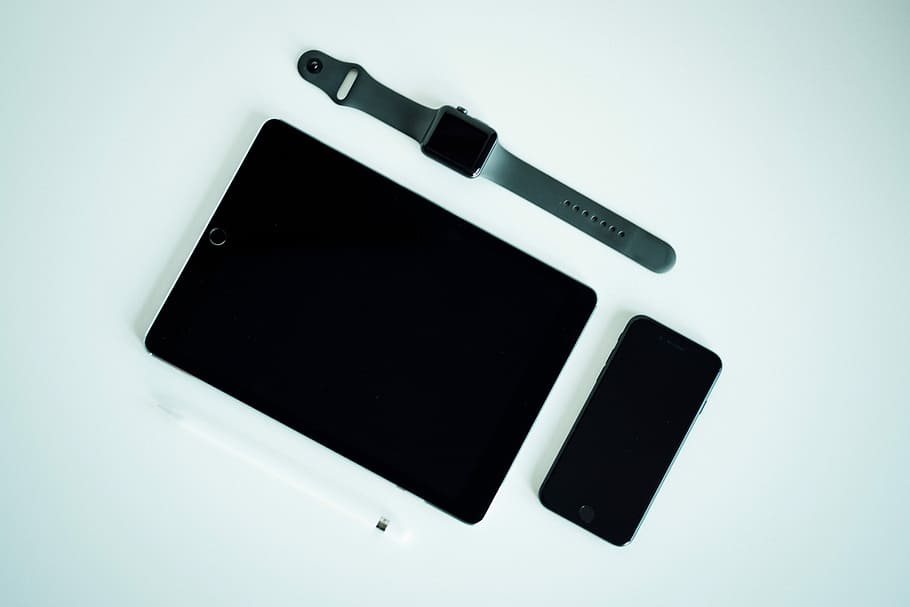black iPad, post-2017 iPhone, and black aluminum case Apple Watch with gray Sport Band, black iPad