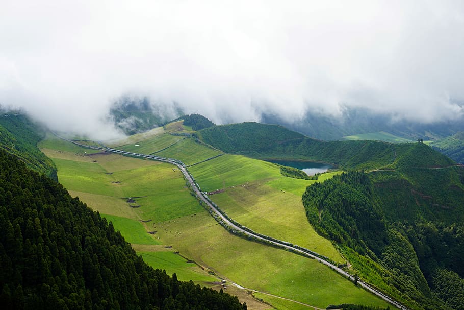 road between green grass field near mountains under white sky at daytime, scenery of a volcano under white clouds HD wallpaper
