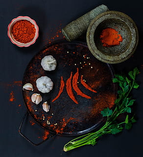 round steel plate with red powder and two garlic heads on top HD wallpaper