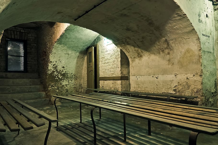 brown wooden bench under arch concrete pillar at nighttime, bunker