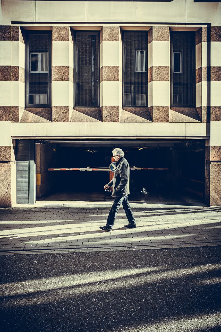 man walking on pavement in front of concrete structure, man walking beside parking lot HD wallpaper
