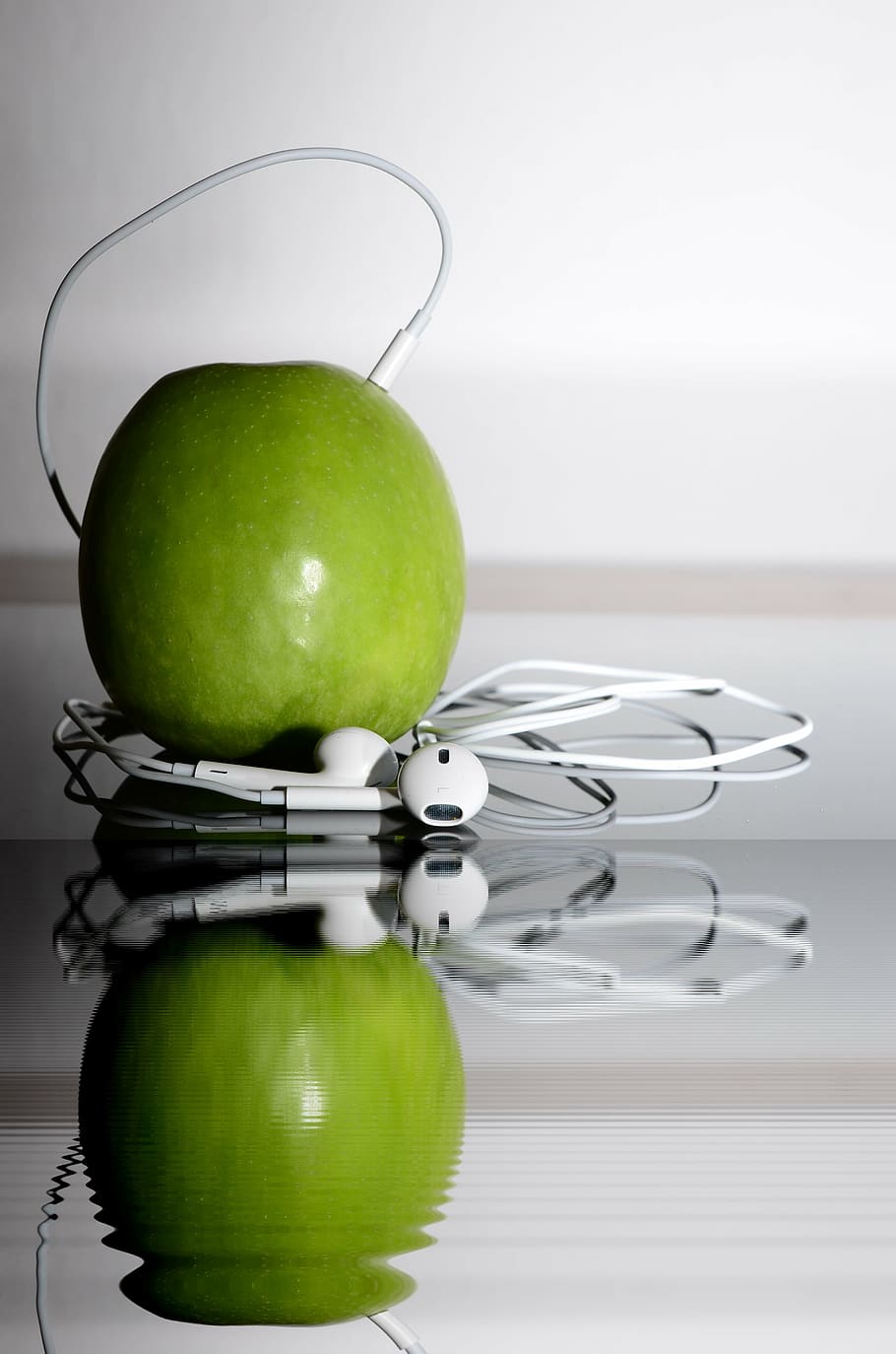 close-up photo of green apple fruit beside white Apple EarPods
