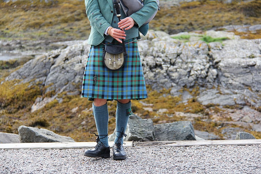 person carrying bag pipe, bagpipes, kilt, highlander, scottish