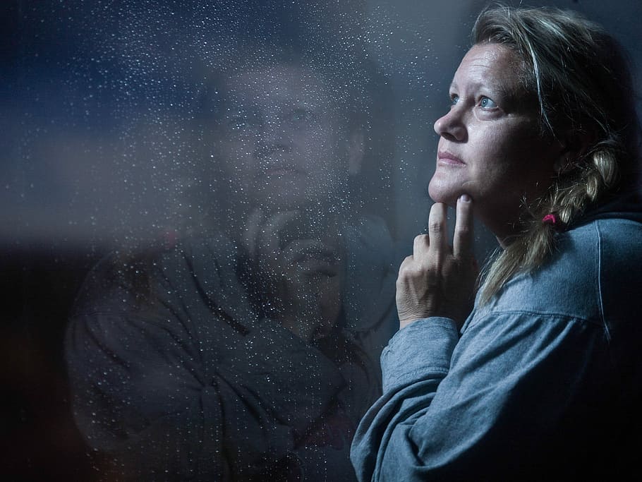 woman standing in front of glass thinking while holding chin HD wallpaper