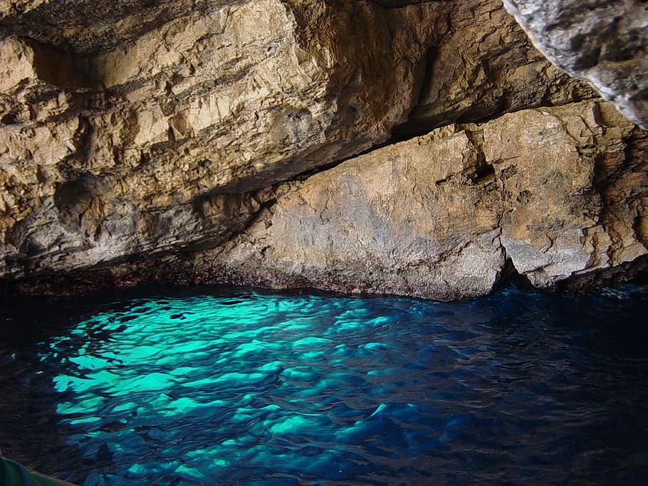 cave with body of water during daytime, blue grotto, sea, island