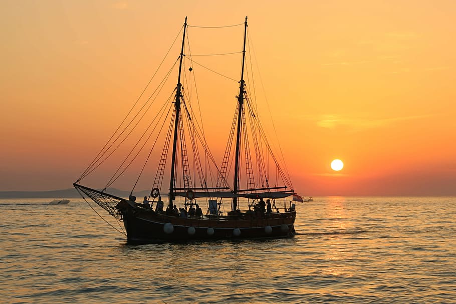 black and white sailboat in body of water during sunset, black sailing ship on body of water
