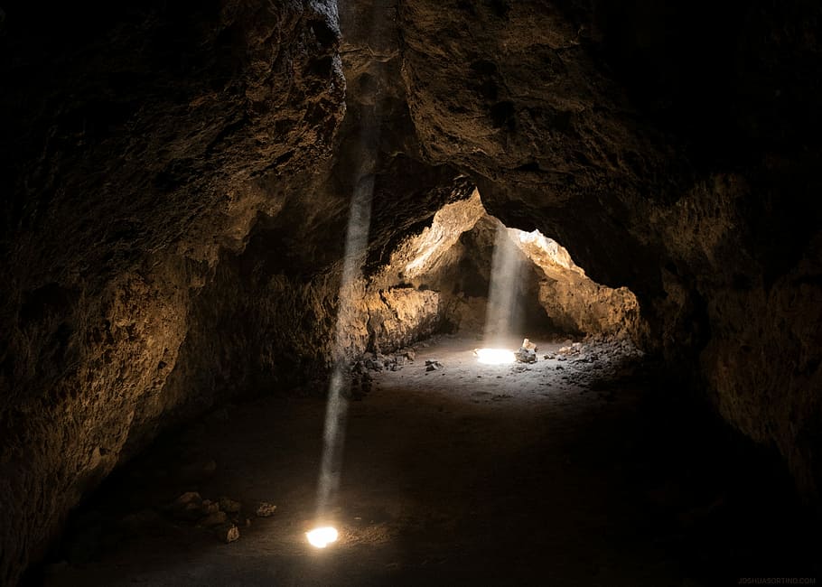 photo of light towards inside of cave, empty cave with sun two lights