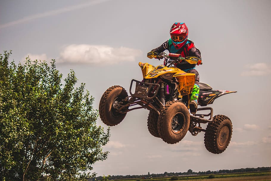 person riding yellow and black ATV, person on yellow and black ATV quad bike during daytime
