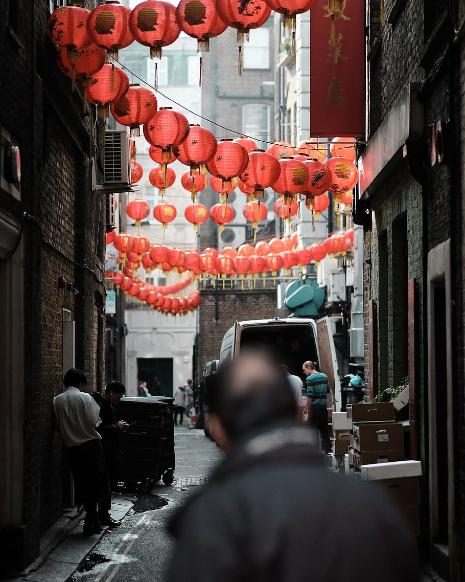 people standing under red Chinese lanterns between high-rise building during daytime HD wallpaper