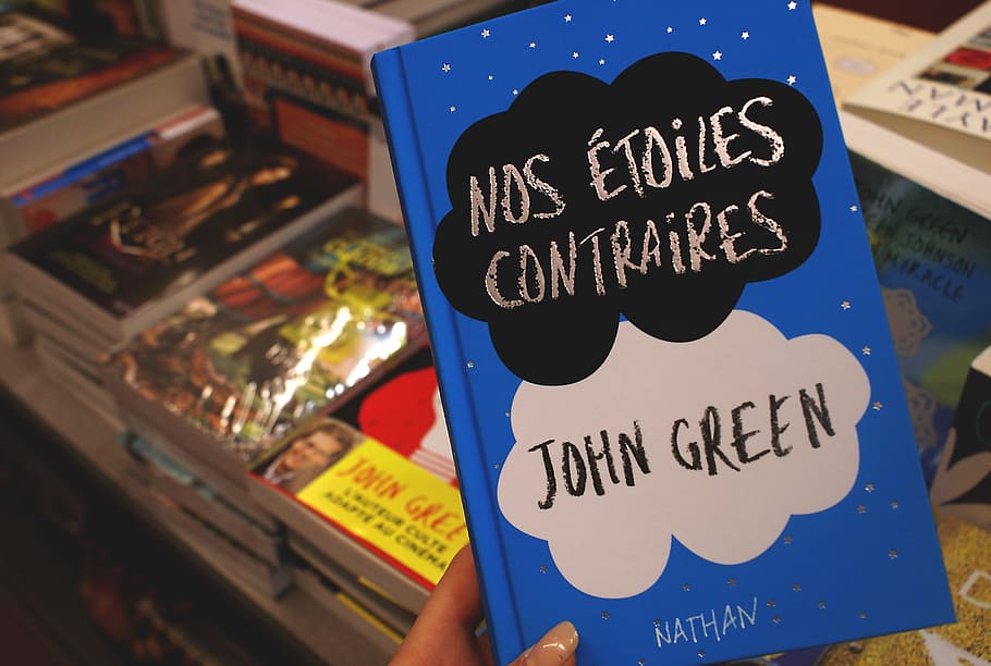 person holding Nos Etoiles Contraires by John Green book, cover