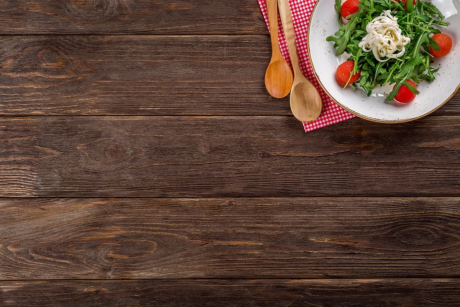 salad on white ceramic plate on brown wooden table, background