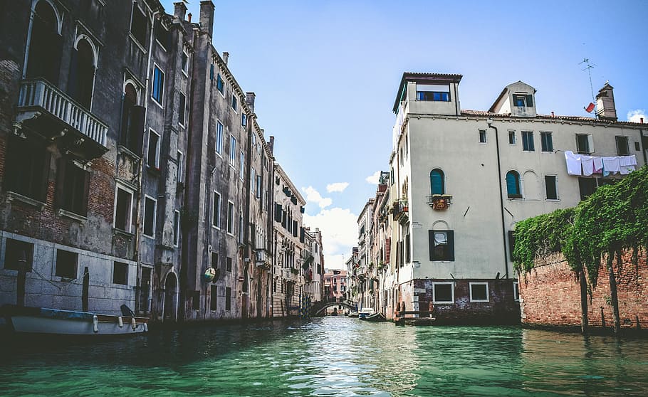 white boat beside gray concrete building during daytime, body of water between buildings HD wallpaper