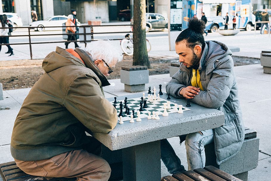 people playing chessboard game outdoor, two man playing chess