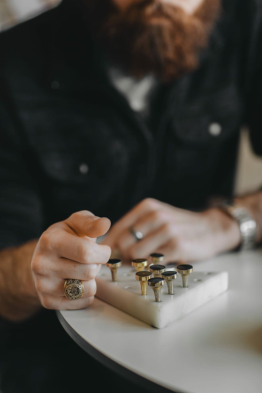 man looking on gold-colored taper gauge on desk, person's hand wearing gold-colored signet ring near handheld tool HD wallpaper