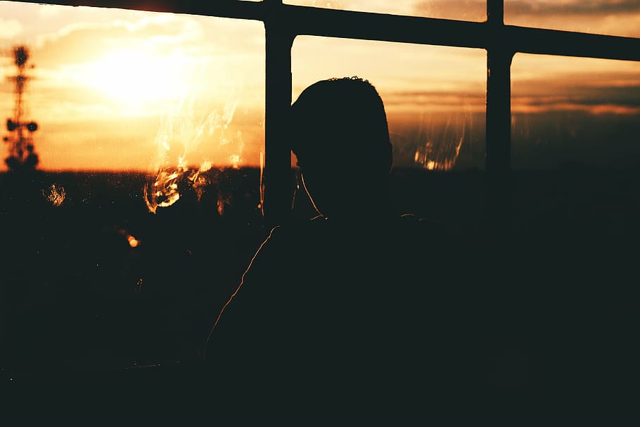 silhouette of man sitting near glass window, sunset sky, viewing HD wallpaper