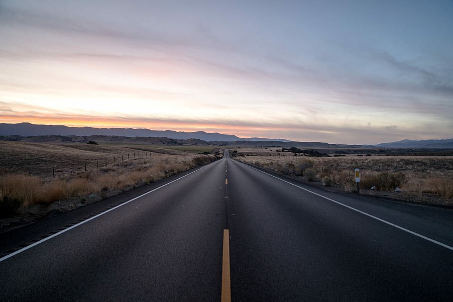 black concrete road between steppe, asphalt road in between grass field during daytime HD wallpaper