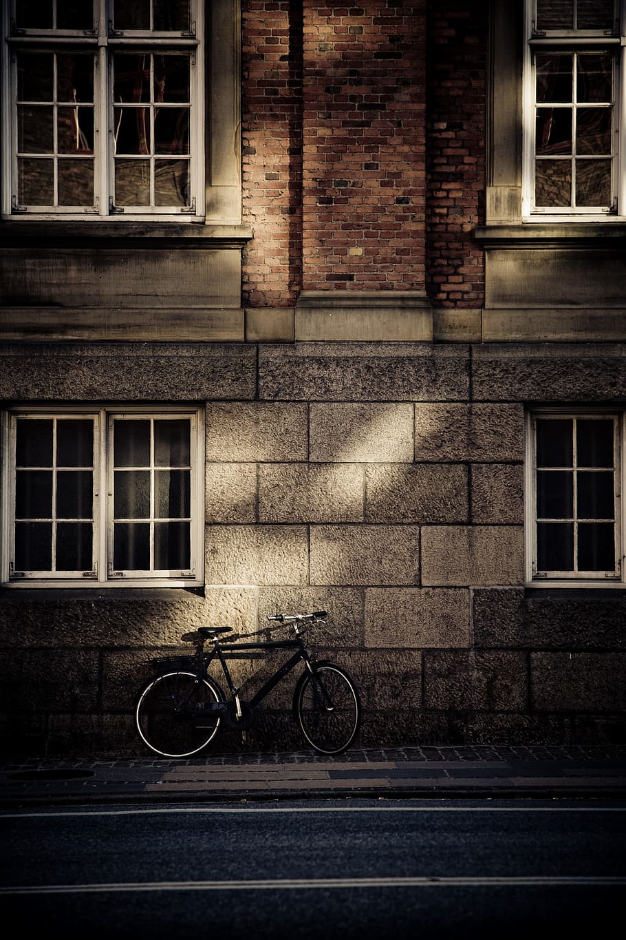 black mountain bicycle in front of brown concrete house, black road bike on gray wall