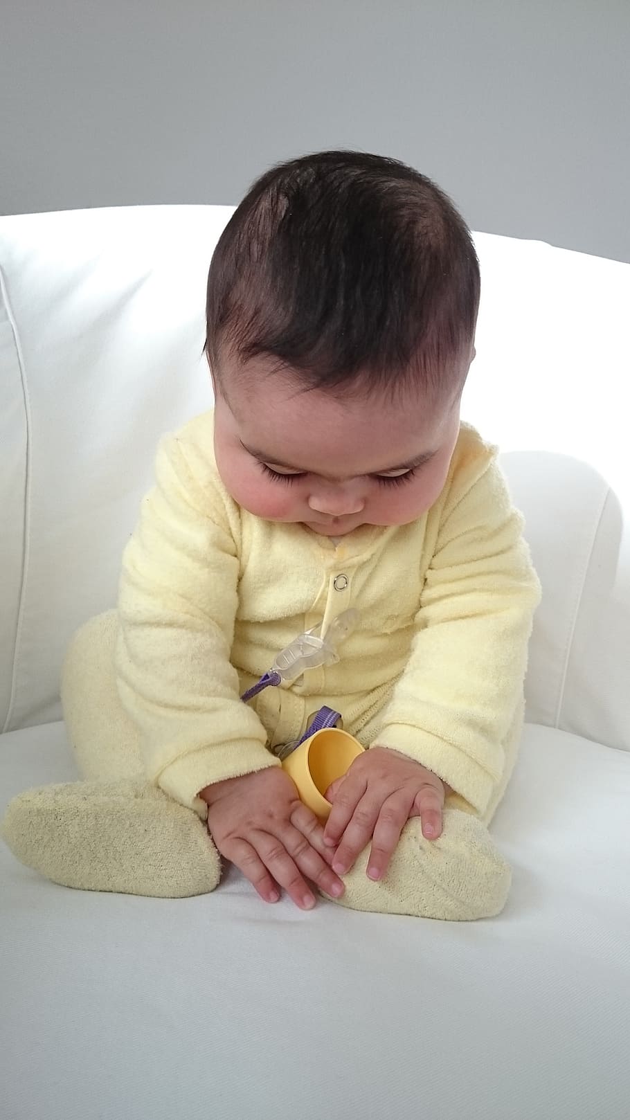 baby sitting on white sofa chair, the strenght is to be found in serenity