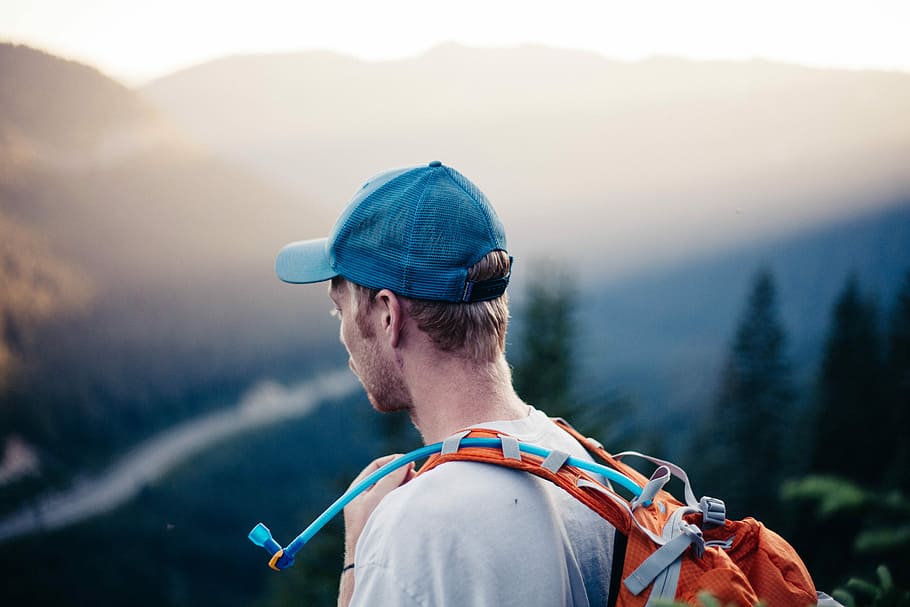 man wearing white shirt with orange hydro backpack, man carrying orange backpack with hydration pack HD wallpaper