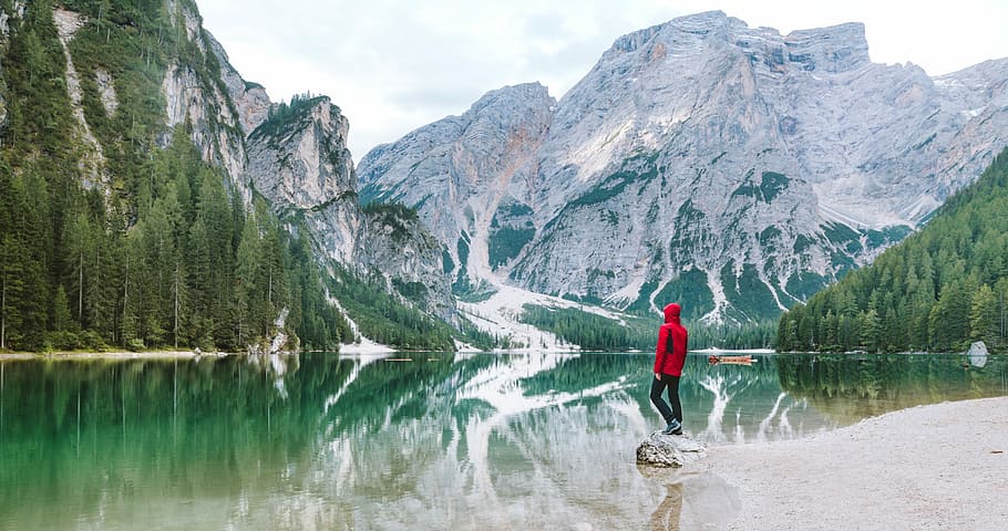person standing on rock in Banff National Park, California, person in red pullover hoodie standing in front of body of water HD wallpaper