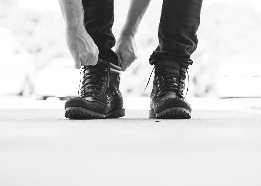 person wearing black leather lace-up boots, grayscale photo of person wearing black leather work boots