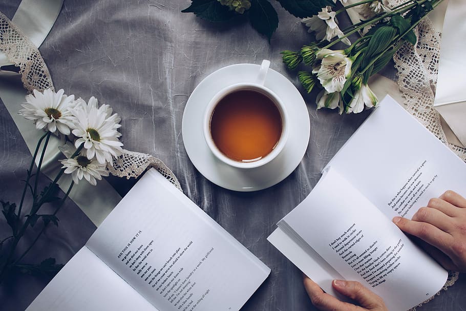 person placing book beside cup and saucer, business, paper, coffee