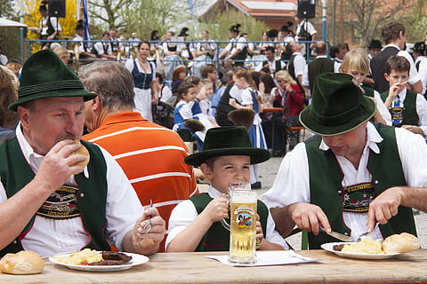 two men and one boy wearing green hat eating on brown wooden table HD wallpaper