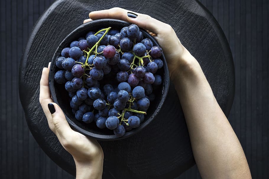 person holding bowl of grapes, person holding bowl of grapes on round black wooden slab HD wallpaper