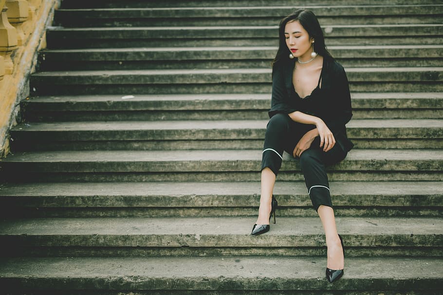 woman sitting on gray stair, woman wearing black dress sitting on the stairs