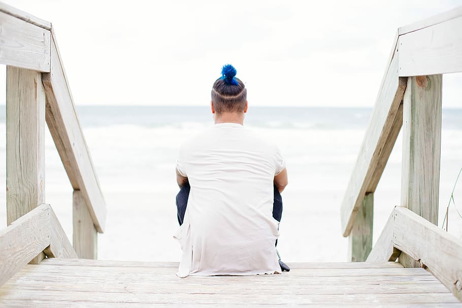 person in white top sitting on stair facing the body of water HD wallpaper