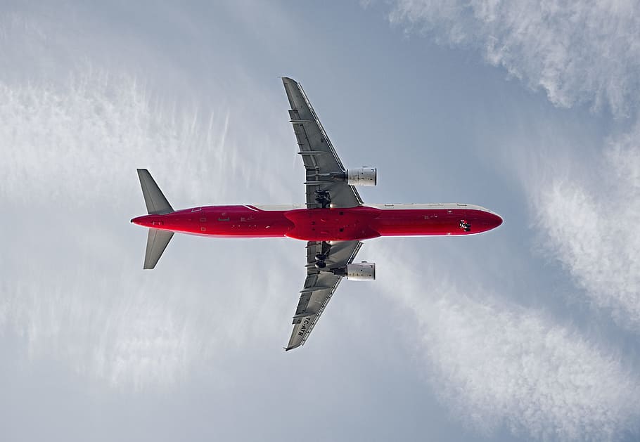 red and white passenger airplane on the sky during daytime, low-angle photography of red airplane flying under white clouds and blue sky HD wallpaper