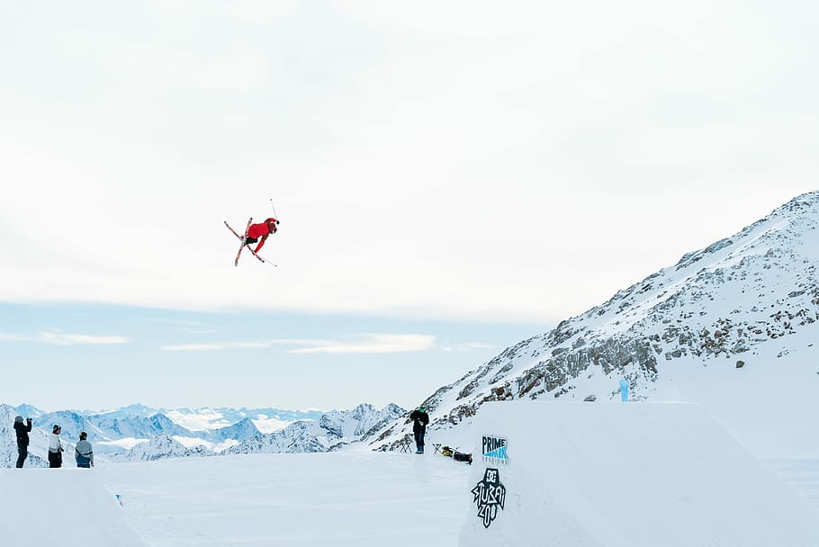 person hovering over snow covered ground during daytime, man ski boarding during daytime HD wallpaper