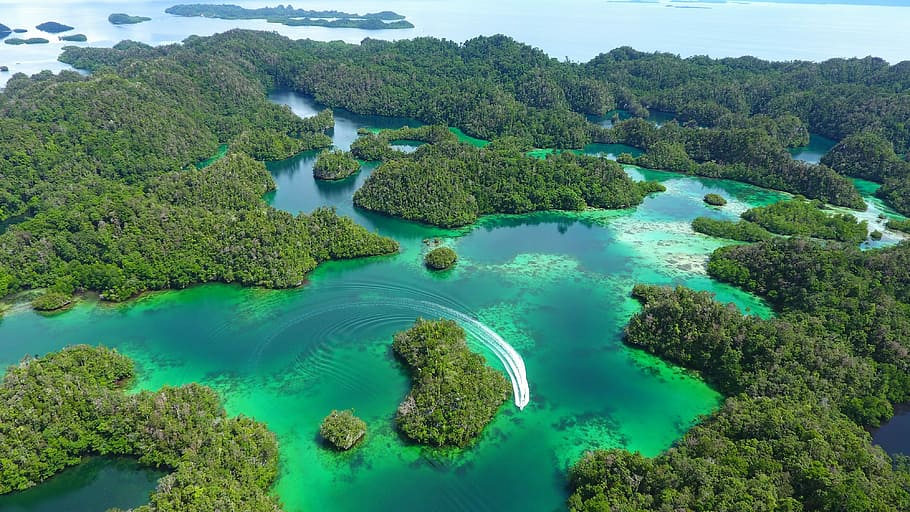 bird's eye view photo of islets during daytime, speedboat traveling on a archipelago