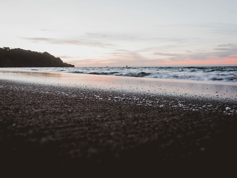 low angle photo of sea shore, seashore near mountain during day time HD wallpaper
