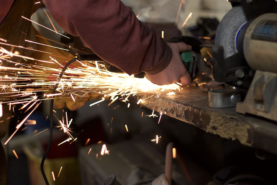 person wearing brown sweater holding circular saw, sparks, grind