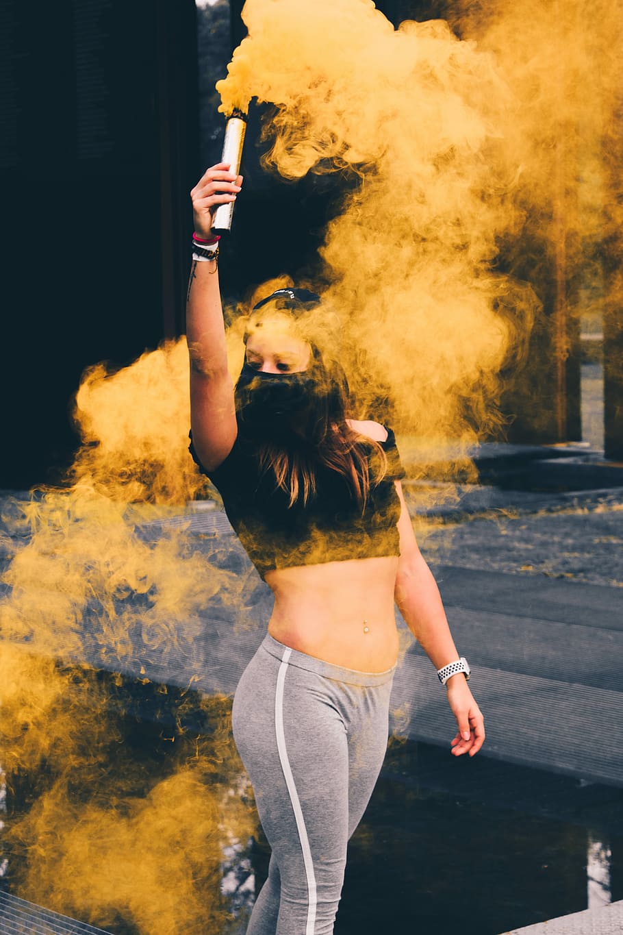 macro photography of woman wearing mask while raising smoke bomb, person holding smoke tube