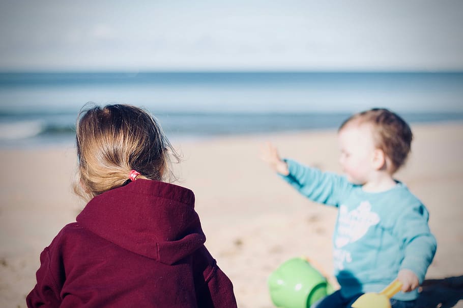 two toddler's sitting on seashore, children on beach photo during daytime HD wallpaper