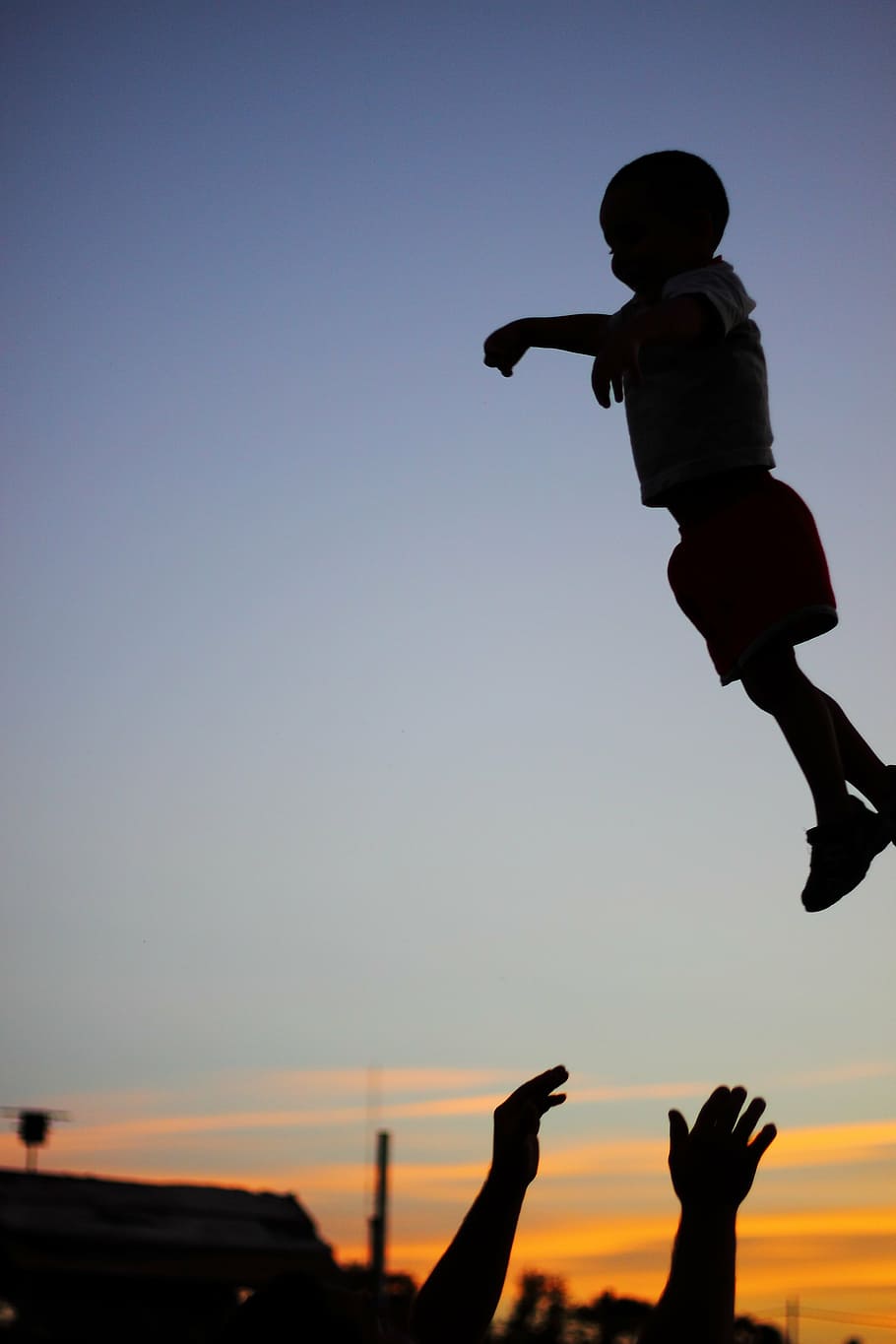 silhouette photography of child on air with a person catching him HD wallpaper