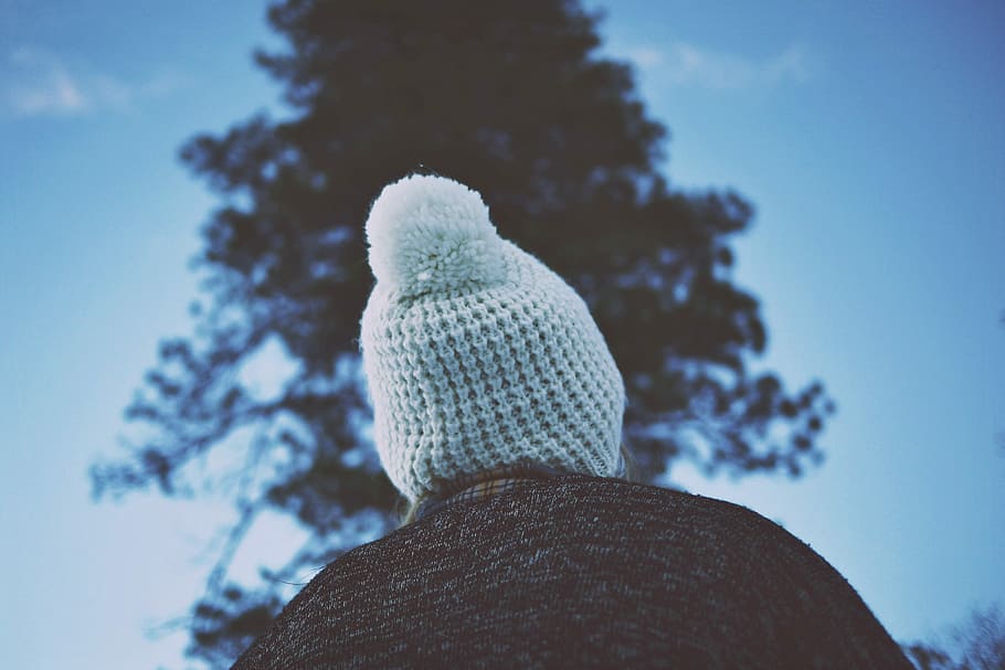 person in front of tree during daytime, low angle of person wearing knit cap